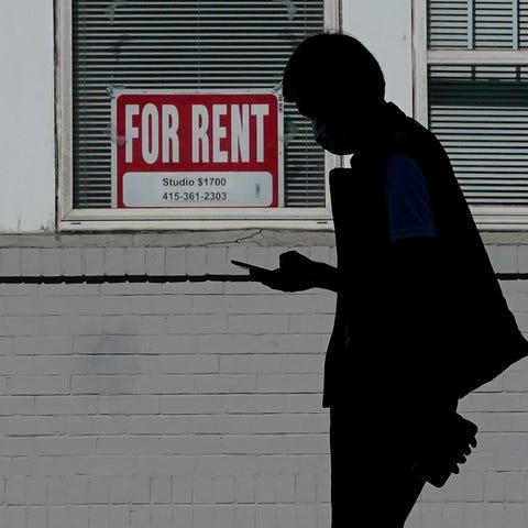 A man walks in front of a "For Rent" sign in a win