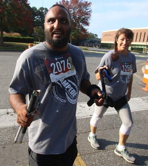 Gaston College Officer Crystal Todd helps lead blind Gaston College alum Angus Kola as they near the finish line during the inaugural Stampede for Student Success 5K Run held Saturday morning, Oct. 2, 2021, on the campus of Gaston College in Dallas.