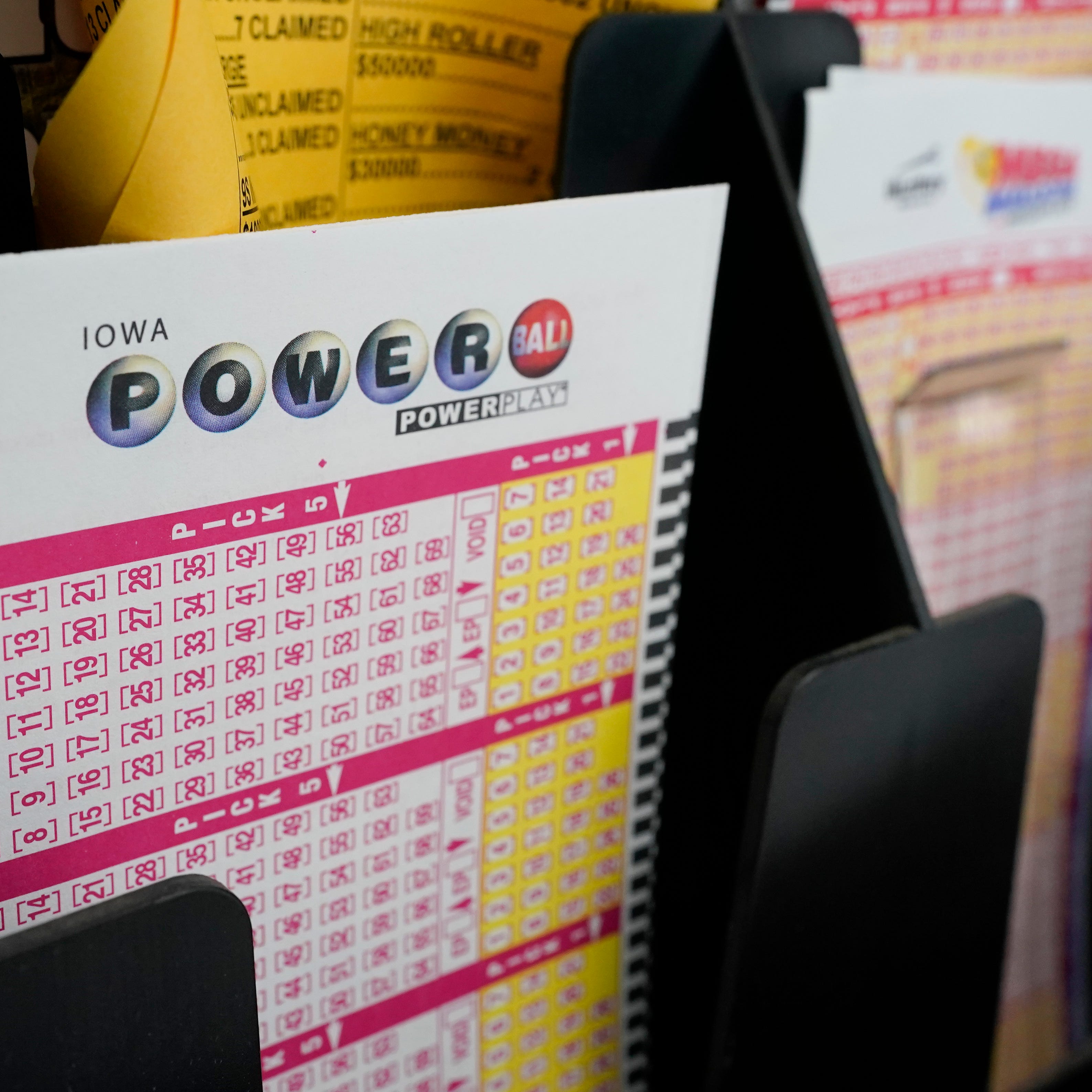 In this Jan. 12, 2021 file photo, blank forms for the Powerball lottery sit in a bin at a local grocery store, in Des Moines, Iowa. The giant Powerball jackpot has grown even bigger, with officials raising the estimated payout ahead of Saturday, Oct. 2, drawing.