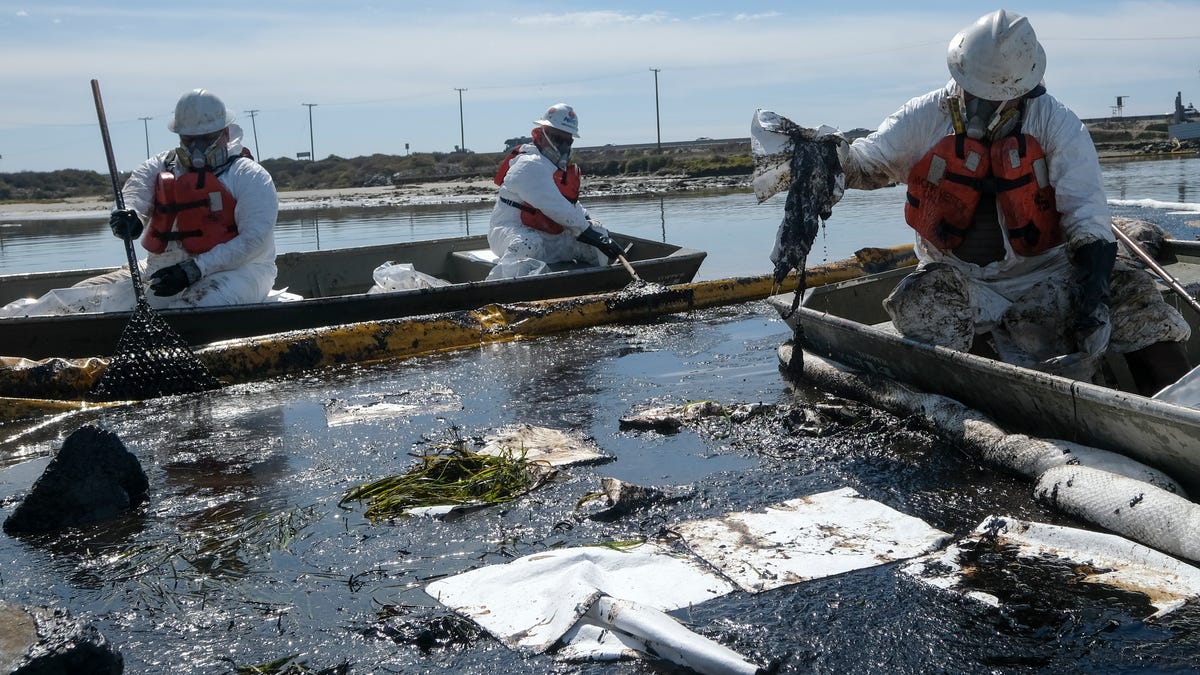 Cleanup contractors deploy skimmers and floating barriers known as booms to try to stop further oil crude incursion into the Wetlands Talbert Marsh in Huntington Beach, Calif., Sunday, Oct. 3, 2021.