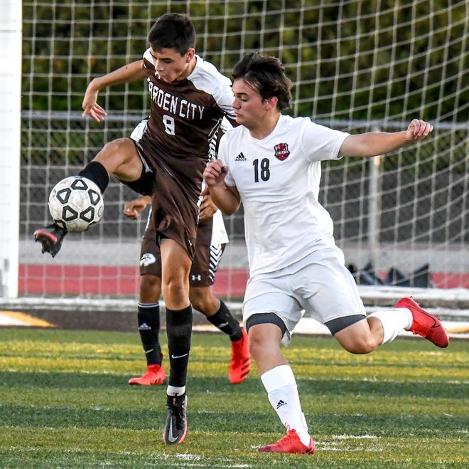 Garden City High School's David Hernandez, left, leaps in the air to move the ball upfield away from Wichita Heights Toller Phipps Monday at Buffalo Stadium.