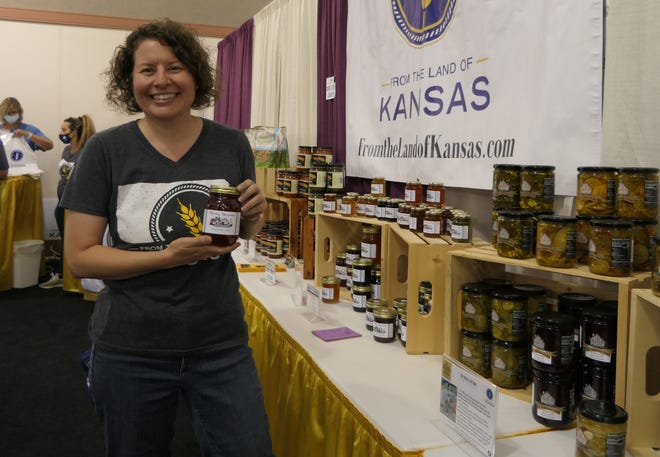 Janelle Dobbins, a manager with From the Land of Kansas, holds up a jar of Sticky Spoons jelly, which is made in Hutchinson, in September in the KDA booth at the Kansas State Fair.