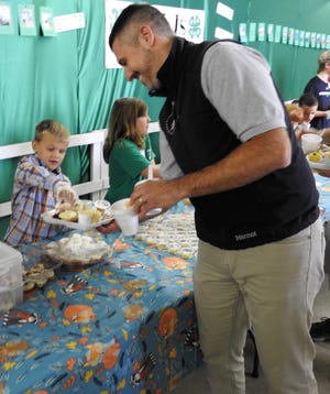 Laramie Massie, 7, a Cloverbud, gives a pumpkin cookie to Jason Given at the Tasting Smorgasbord at the Coshocton County Fair.