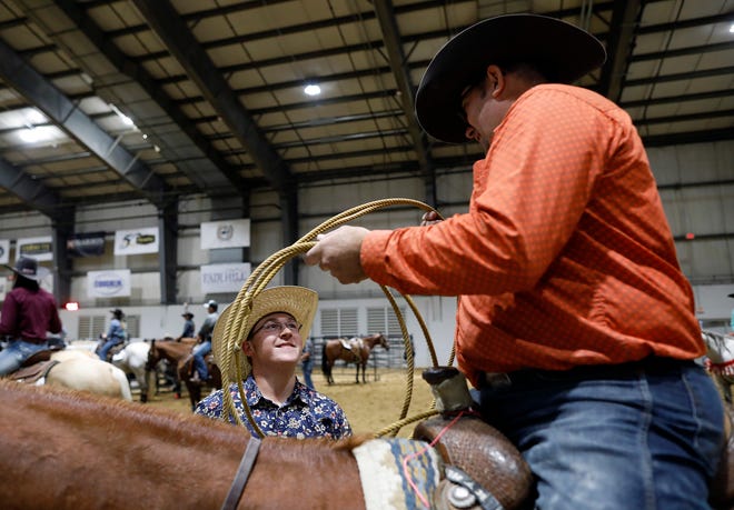 Brady Schaad, left, 18, of Cumberland helps his dad, Aaron, 51, get ready before a breakaway roping competition in the Celeste Center Thursday. Aaron Schaad finished fourth in the event.