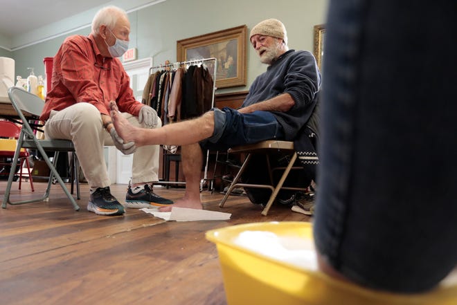 Doctor Douglas Fogg takes a closer look at the feet of David, a homeless man, during the weekly Mercy Meals and More podiatry clinic for homeless people on Purchase Street in New Bedford.