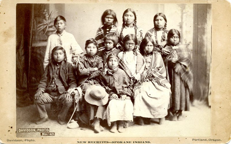 The second group of Spokane students taken from the band of Chief Lot as photographed July 8, 1881 in a Portland studio on the way from their homes to the school. Their names as given on the school roster are: Alice L. Williams; Florence Hayes; Suzette (or Susan) Secup; Julia Jopps; Louise Isaacs; Martha Lot; Eunice Madge James; James George; Ben Secup; Frank Rice; and Garfield Hayes.
► The Forest Grove Indian School Superintendent has this photograph made for fundraising and promotional purposes, according to the Pacific University Archives. It is intended to be a "before" picture, which he pairs with a later "after" picture that was taken when the children had been at the school for seven months.