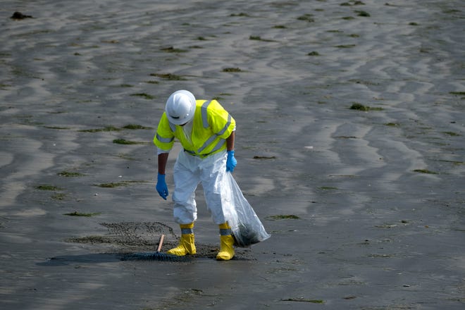 A worker in protective suit cleans the contaminated beach after an oil spill in Newport Beach, Calif., on Wednesday, Oct. 6, 2021.