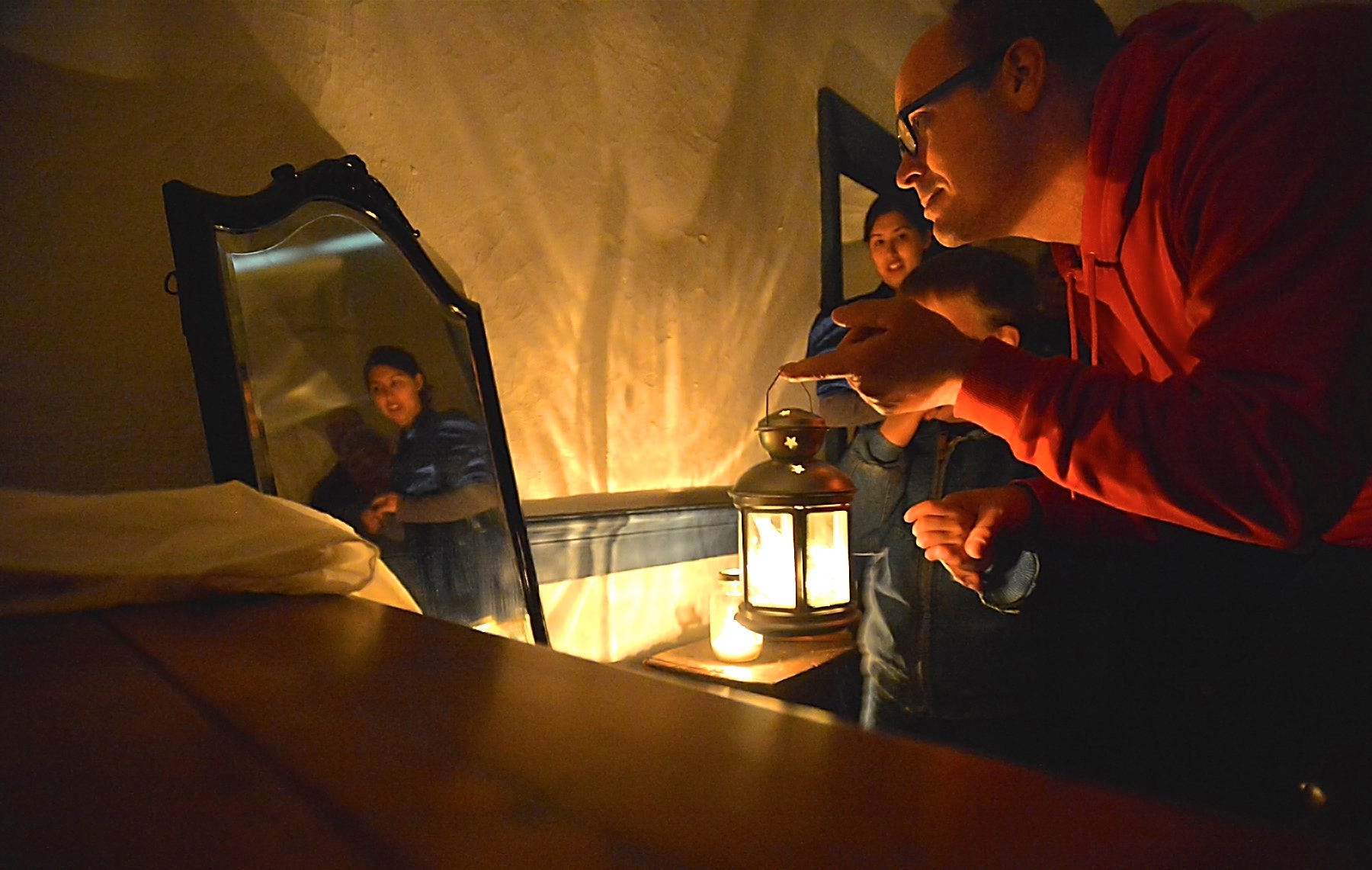 In this file photo, Joseph Harne, holding the hand of his son Lakin Smith, peers into a mirror that some say reveals ghostly images. They were on a ghost tour of the Hager House in City Park. The woman's reflection is that of former Hager House curator Sarah Chang.