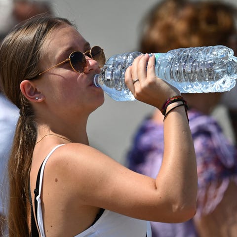 A woman drinks water from a bottle to cool off fro