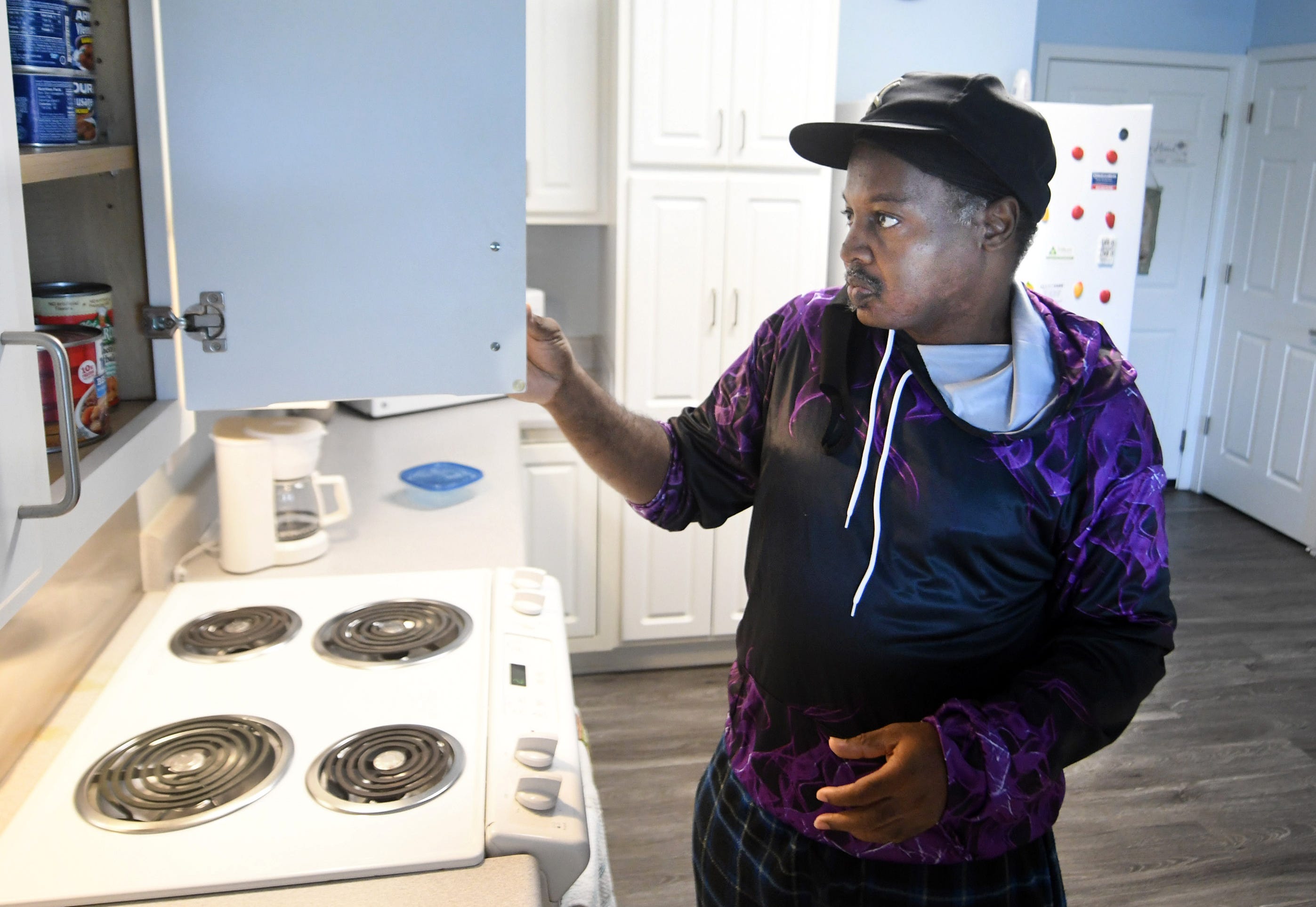 Greg Planter looks through his cabinets in his apartment at Lakeside Reserve in Wilmington, North Carolina, in July 2021. Planter was homeless for about a year before finding a spot at a local shelter in 2016. While staying there, he was able to get on disability and obtain housing vouchers, which led him to find a more permanent housing option.