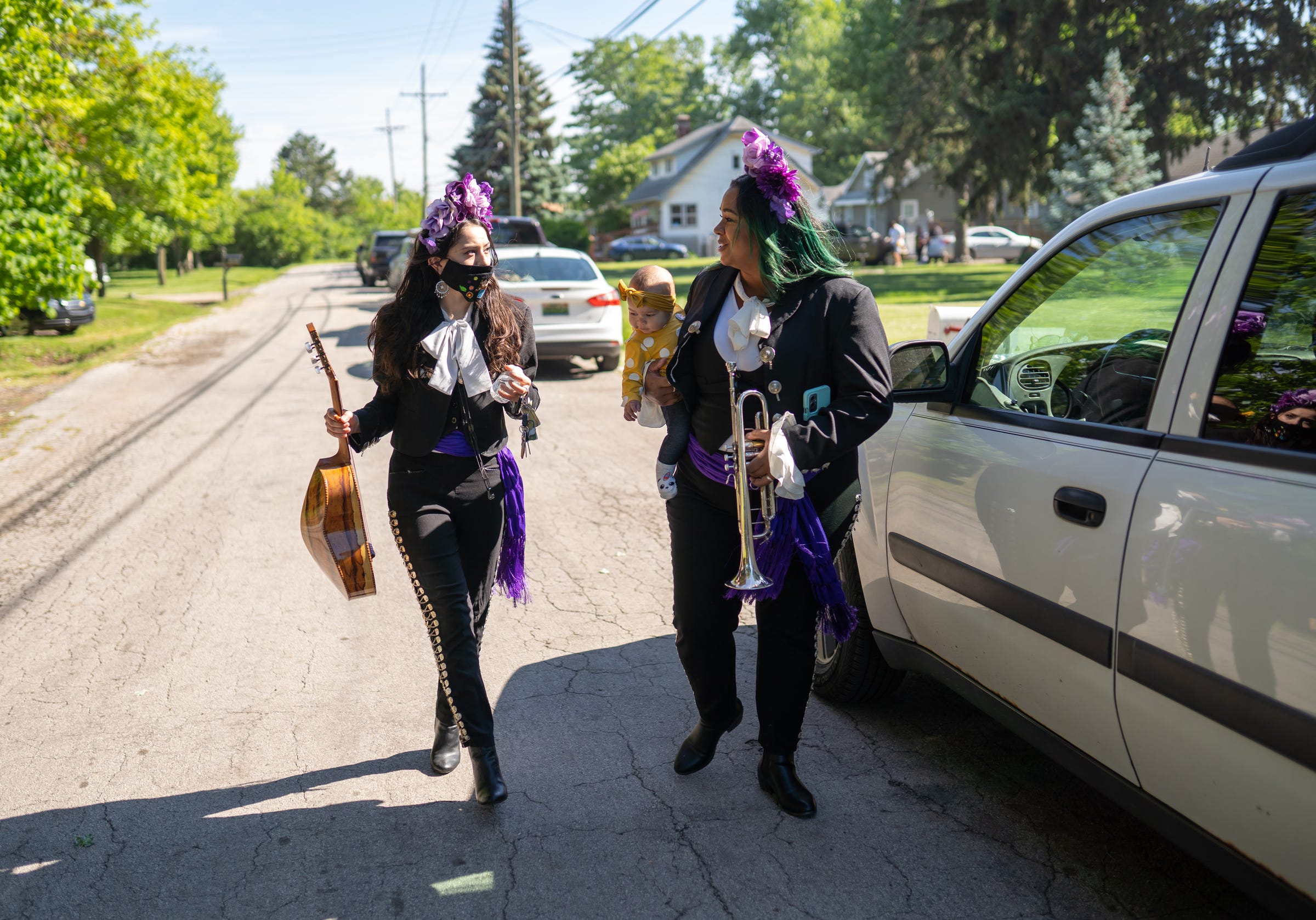 Mariachi Femenil Detroit director Camilla Cantu, of Detroit, talks with Sherray Rowe, of Livonia, as she carries her daughter Morgan ahead of a gig in Taylor on Saturday, May 29, 2021. "All my music members are moms except for me. It's a very unique niche I think when mariachi women are bringing their children to their events," said Cantu. "Sherray came to us with a toddler and Rita had her baby a year into the group so we just had to adapt. She kept saying I don't know if I can play but we kept telling her to bring your baby to practice. Bring your husband to practice. I don't care who comes."