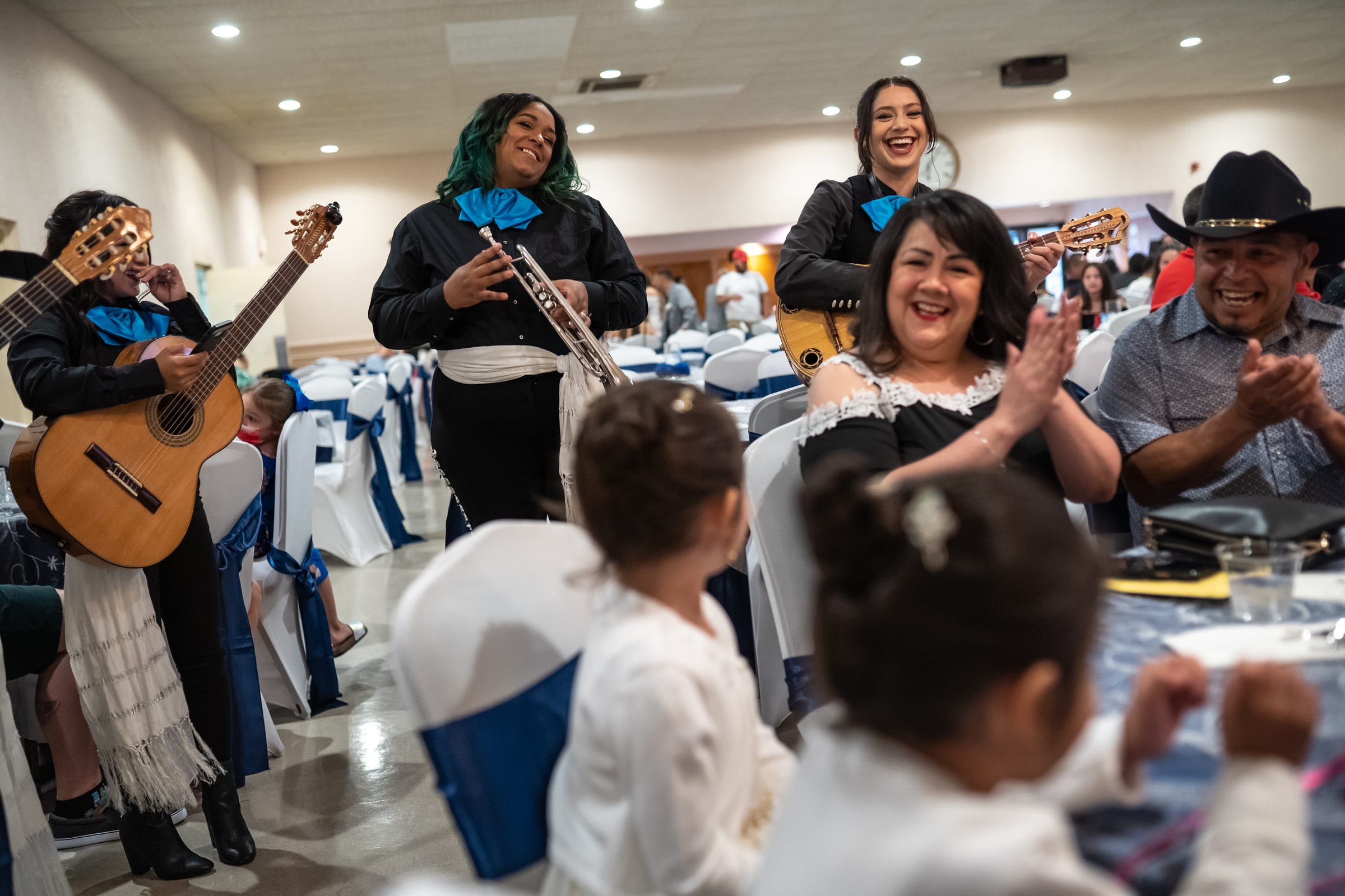 (Background right to left) Mariachi Feminil Detroit director Camilla Cantu shares a laugh with members Sherray Rowe, of Livonia, and Rita Ramirez, of Detroit, while performing during a quinceañera for Amelia Araceli Angiano at Sts. Peter & Paul Banquet Hall in Dearborn Heights on Saturday, June 12, 2021.