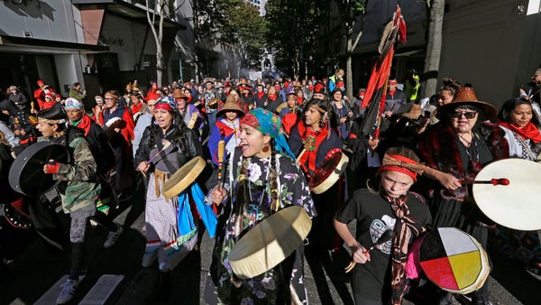 Drummers sing as they lead a march during an Indig