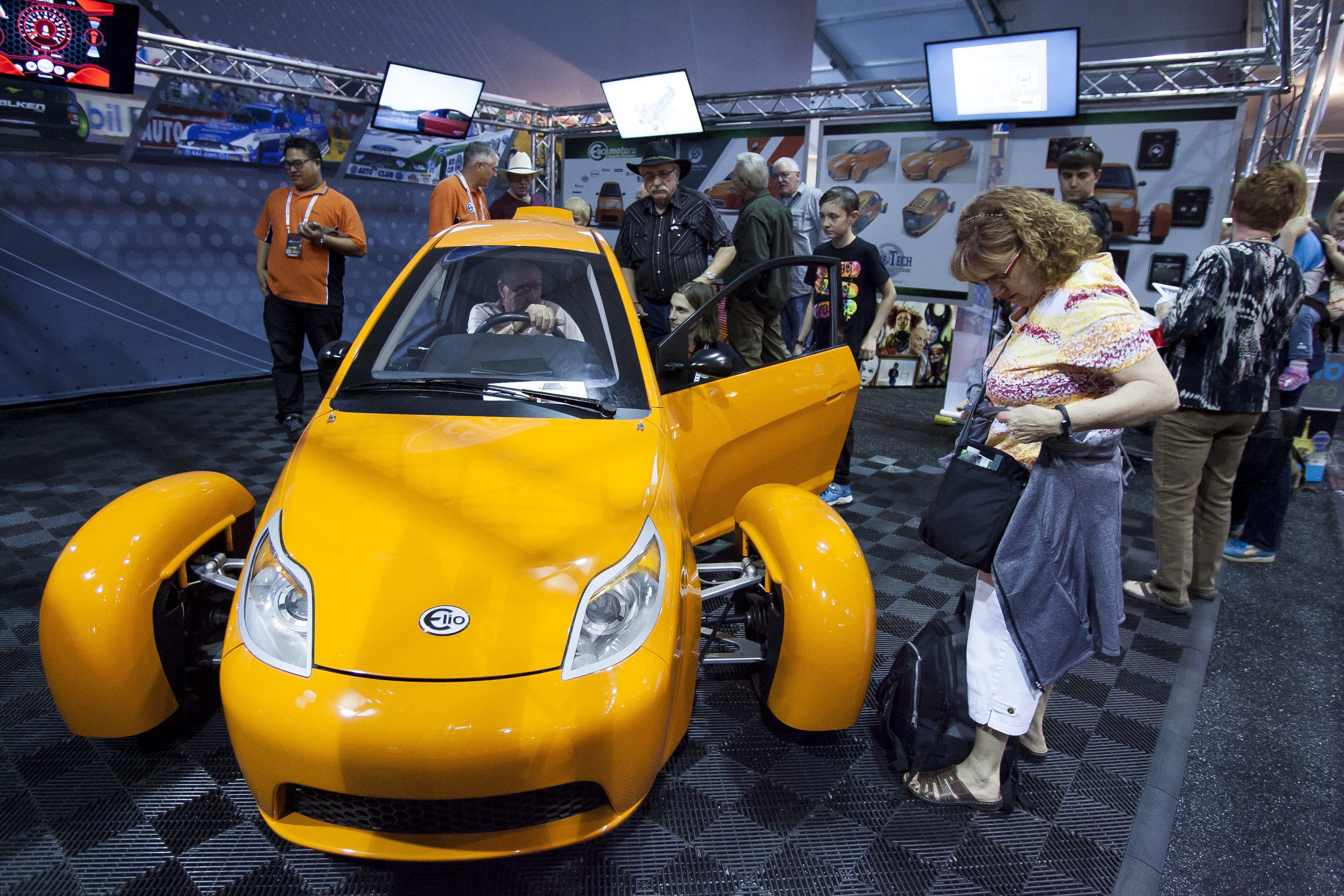 Spectators take turns sitting in an Elio prototype vehicle on the opening day of the Barrett-Jackson Collector Car Auction on Jan. 10, 2015, at Westworld of Scottsdale in Scottsdale, Ariz.