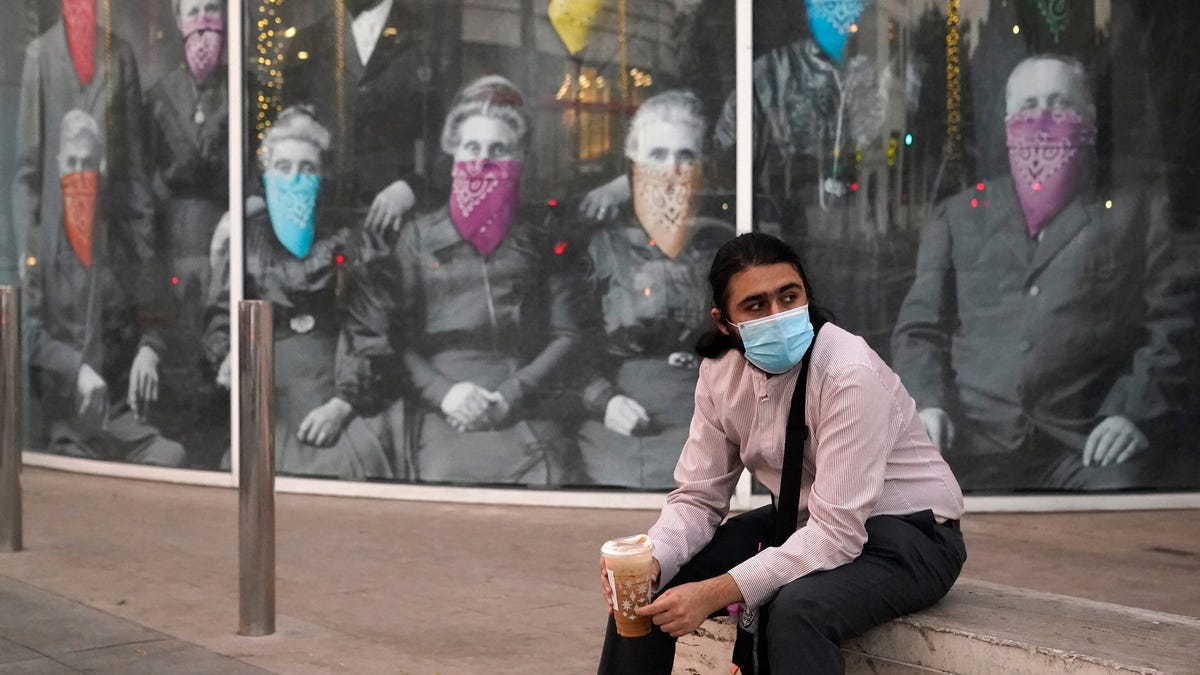 A man takes a coffee break in front of a COVID 19-themed mural, in Beverly Hills, Calif., Wednesday, Dec. 9, 2020. On Monday, Oct. 11, 2021, California's coronavirus death toll reached 70,000.