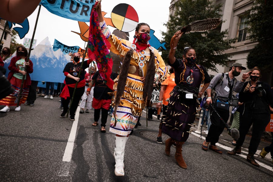 Demonstrators dance and march in honor of Indigenous Peoples Day at Freedom Plaza on Oct. 11 in Washington. Activists organized the march to the White House to demand that President Joe Biden stop approving fossil fuel projects and declare a climate emergency before a United Nations climate summit in November.