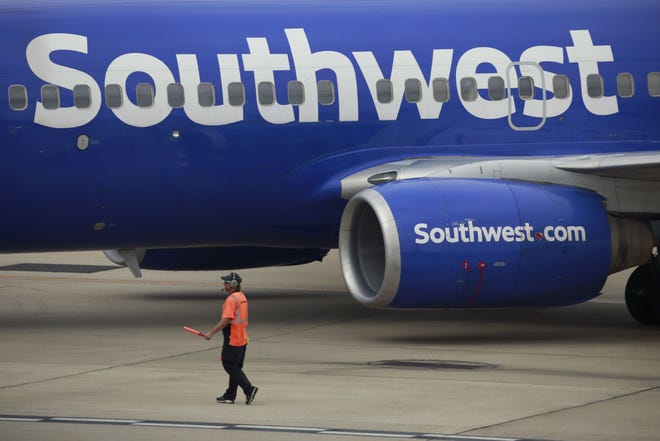 A worker directs a Southwest Airlines Boeing 737 passenger jet pushing back from a gate at Midway International Airport in Chicago on Oct. 11, 2021.