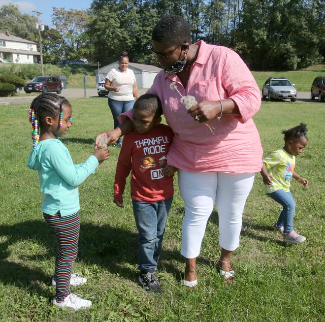 Charlene Taylor, owner of Nunu's Family Child Care at Friendship Baptist Church in Massillon, is offered a flower from Heavenly Spellen, left. Also pictured are William Hopkins, second from left, and Leilani Young, far right. Pictured in the background is Jennifer Horner, daycare administrator.