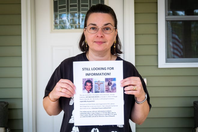 Maureen Harrington, sister of Christopher Demrose, poses for a portrait with a flyer she made asking for information Tuesday, Oct. 12, 2021, at her home in Lexington. Demrose, 48, of Berlin Township, was killed in a fatal hit-and-run crash Oct. 5, 2012.