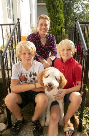 Jennifer Davis, shown Thursday, Oct. 14, 2021 sitting with her two sons 12-year-old Felix, left and Jake, 9, and their Golden Doodle dog Maple, in front of their Pinckney home. Radio host JoAnne Purtan will compete in a "Celebrity Lip Sync Battle" on behalf of Davis, a Pinckney High School teacher battling breast cancer.