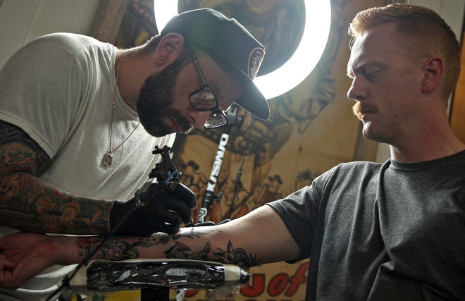 Garrett Potts, left, tattoos John Kroll, right, at his studio in San Angelo on Wednesday, Oct. 13, 2021. Potts, who has been a tattoo artist for over a decade, is now offering restorative cosmetic tattoo services for cancer survivors.