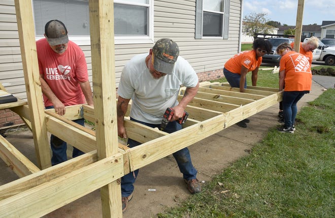 Habitat for Humanity of Monroe's Director of Construction, Ken Christunas (left) and construction manager Jim Worful screw on the next part of a handicap ramp at Jill Sharpe's home in Monroe. They are being assisted by Danyelle Starling, Mandy Chapman and Cris Hardy from the Home Depot store in Taylor.