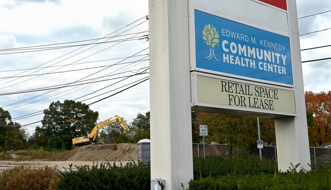 A sign for the current Edward M. Kennedy Community Health Center at 42 Cape Road in Milford with a foundation already under construction for a new facility across the street at 41 Cape Road, Oct. 15, 2021.