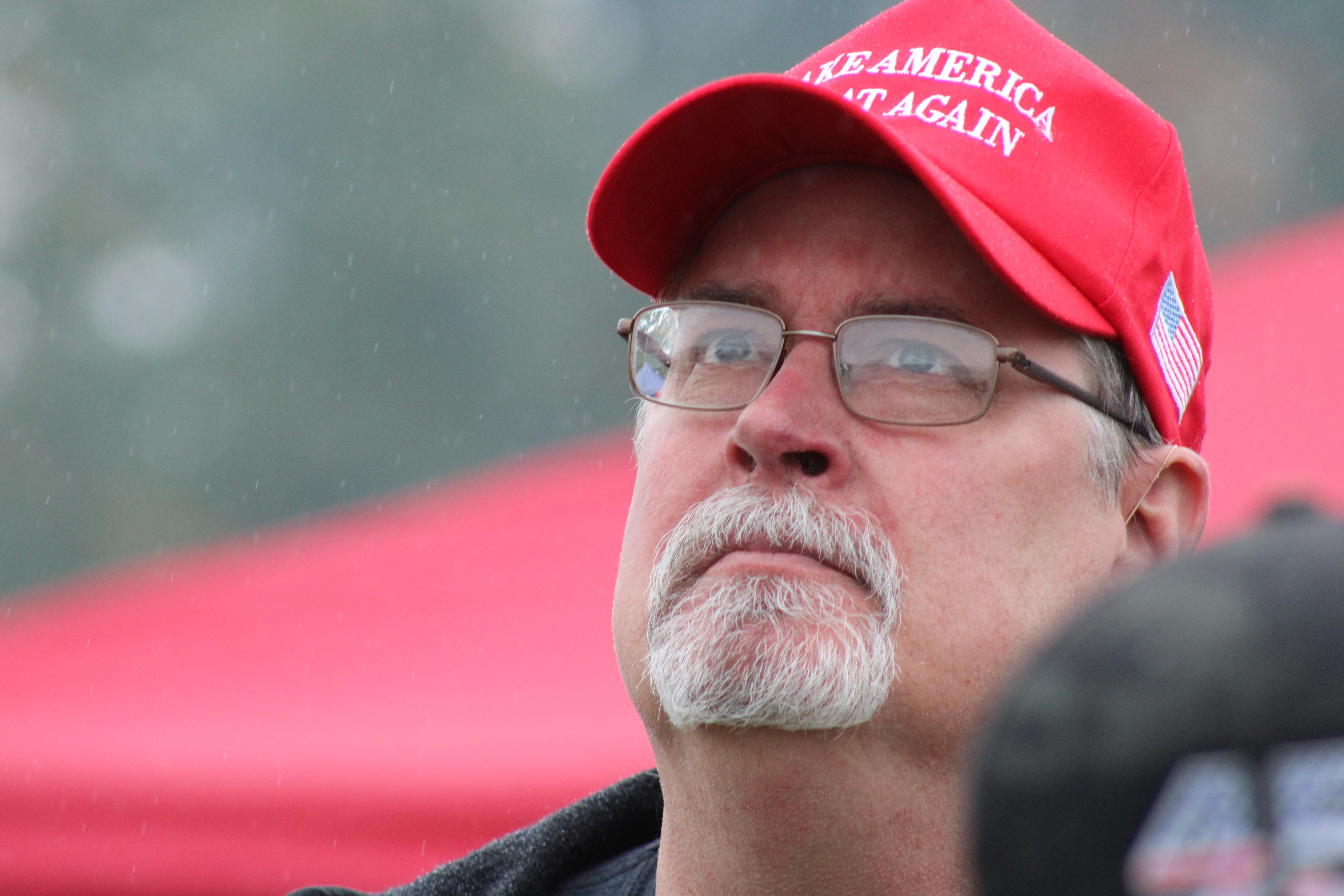 Festival-goers stand in the rain to hear prominent conservative figureheads like Steve Bannon speak at the Rod of Iron Freedom Festival.