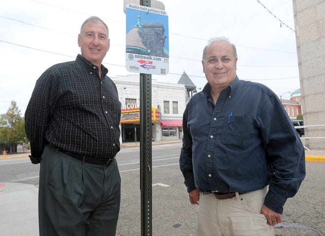 Massillon Rotary Foundation board member Marshall Weinberg, left, and Phil Elum, president of Massillon Main Street, stand with the new self-guided walking tour signs that are being placed around downtown Massillon.
