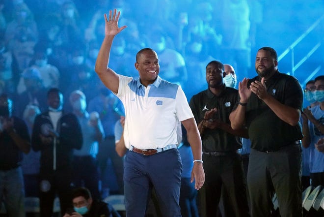North Carolina coach Hubert Davis waves during Late Night introductions as director of player development Jackie Manuel and assistant coach Sean May, right, look on Friday night at the Smith Center.