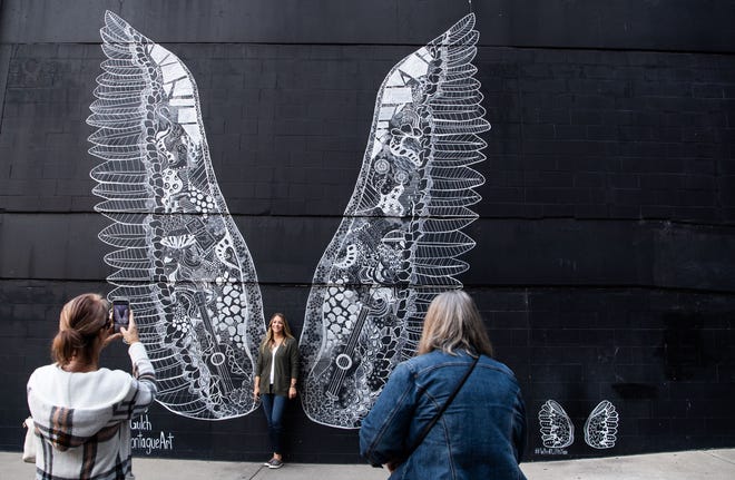 Ashley Spahn stands by the WhatLiftsYou Wings mural while Susan Anderson and Diane Nynas takes picture of her, located at The Gulch on 11th avenue in Nashville, Tenn., Monday, Oct. 18, 2021. 