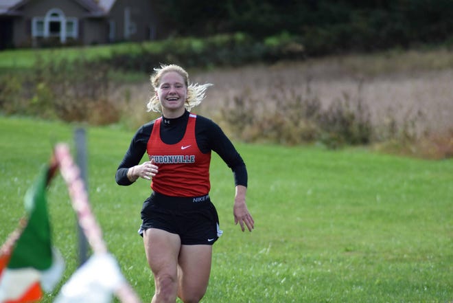 Redbird diistance runner and senior Catlyn Kauffman flashes a big smile as she runs to the finish of the Mid-Buckeye Conference Cross County Championships on Oct. 16 at Loudonville High School, winning her third straight conference title with a personal best time of 20:04.
