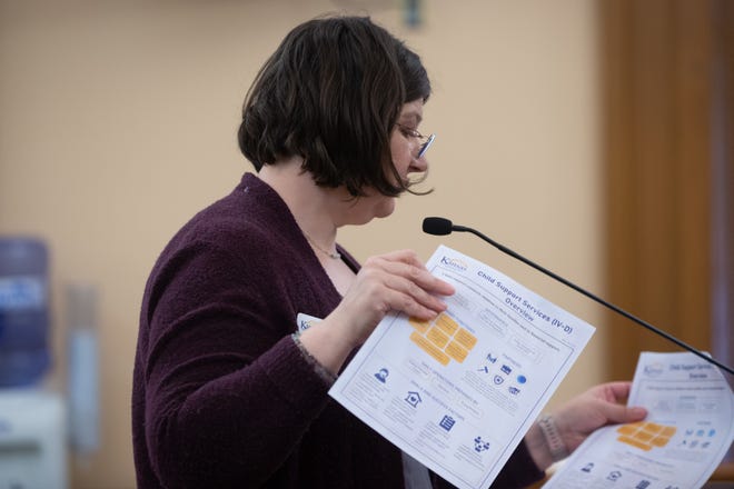 Elizabeth Cohn, director of child support services for the Kansas Department for Children and Families, hands out overview papers regarding the specific services her department handles during a committee meeting Tuesday at the Statehouse.