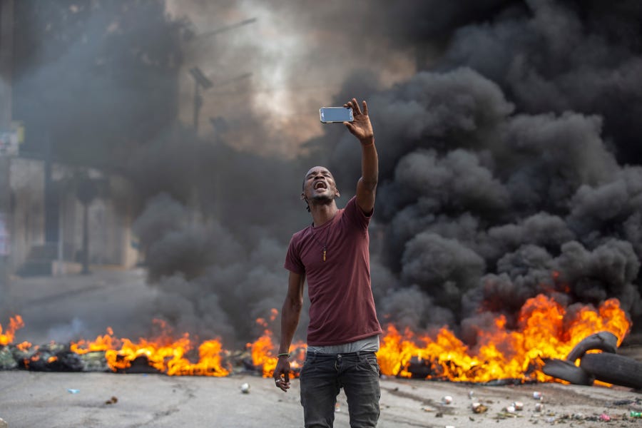 A protester takes a selfie at a burning barricade set by protesters in Port-au-Prince, Haiti, Monday, Oct. 18, 2021. Workers angry about the nation's lack of security went on strike in protest two days after 17 members of a U.S.-based missionary group were abducted by a violent gang. 