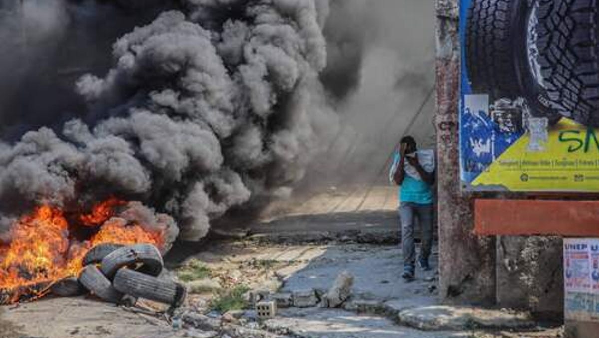 A man walks by tires set on fire after a general strike launched by several professional associations and companies to denounce insecurity in Port-au-Prince on October 18, 2021.
