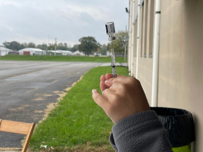 A Marion Public Health worker prepares a syringe for a vaccination clinic at the Marion County Fairgrounds on Oct. 21 in Marion, Ohio. While each syringe is ultimately filled with the vaccine, workers must first dilute the vaccine with 0.9% of sodium chloride.