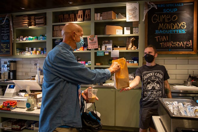 Customer George Cofer picks up his lunch from store employee Jayden Rinderknecht at Royal Blue Grocery on Congress Avenue in Austin on Friday. Royal Blue owner George Scariano said his stores have had to adjust due to the supply chain shortages.