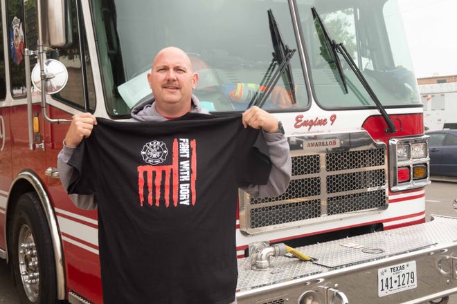 Dory Mogelinski, a local firefighter recently diagnosed with cancer, shows off the T-shirt the local firefighters union had made to raise money for his treatment on Friday, Oct. 22.