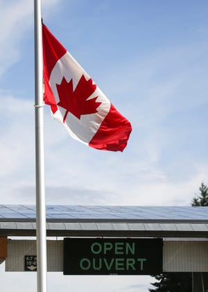 A Canadian national flag flies above an open sign in English and French at a border crossing as Canada reopens for nonessential travel to fully vaccinated Americans in Blaine, Washington on August 9, 2021.