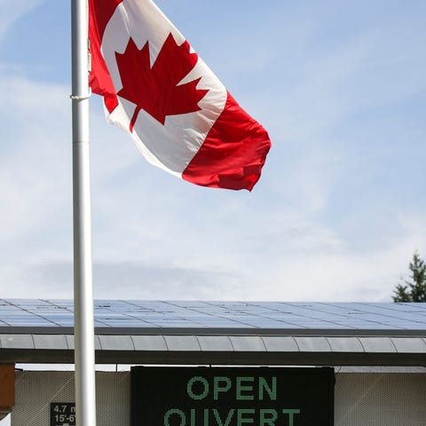 A Canadian national flag flies above an open sign 