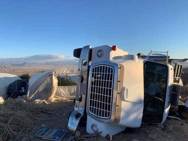A truck lies on its side next to what appears to be an outdoor marijuana grow at an undisclosed location.