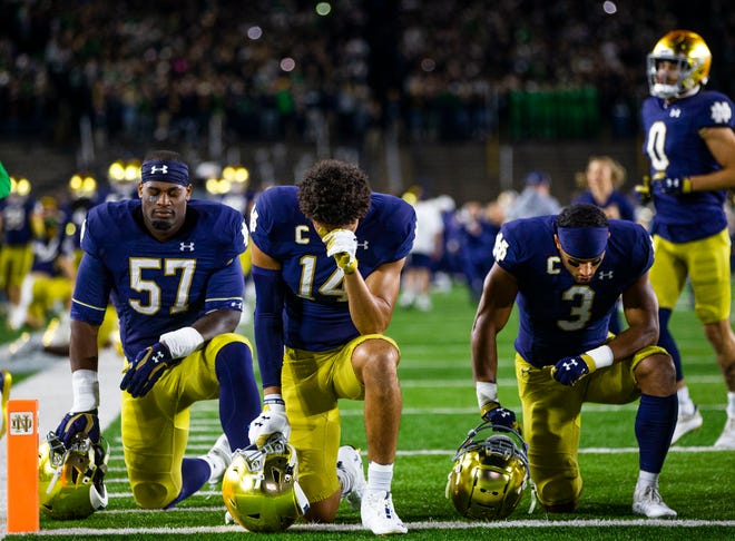 Notre Dame’s Jayson Ademilola (57), Kyle Hamilton (14) and Avery Davis (3) kneel in the end zone prior to the Notre Dame-USC game Saturday, Oct. 23, 2021, at Notre Dame Stadium.