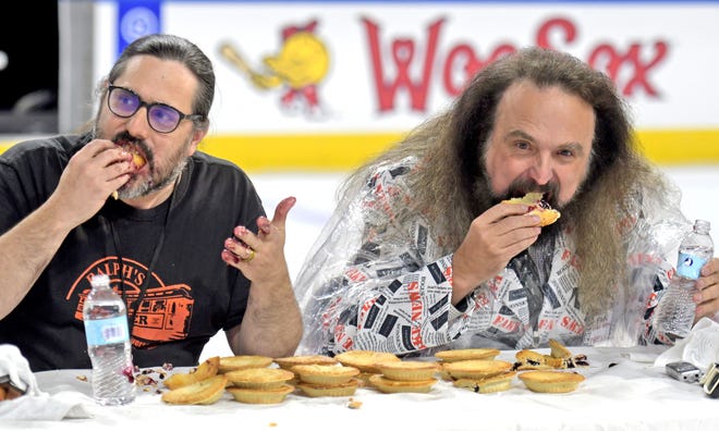 The Telegram & Gazette team of Victor Infante, left, and Craig S. Semon pack away blueberry pies as they challenge professional eater Joey Chestnut during a contest at the Worcester Railers game on Saturday.