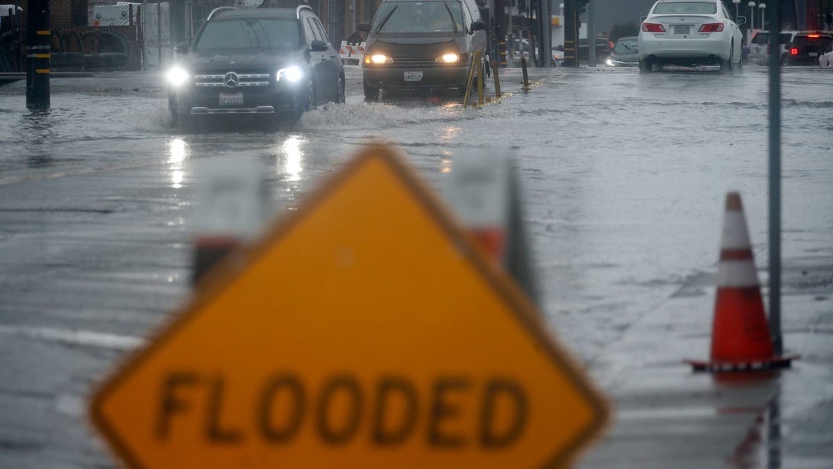Vehicles make their way through a flooded area of High Street near Interstate 880 as rain falls in Oakland, Calif., on Sunday, Oct. 24, 2021.