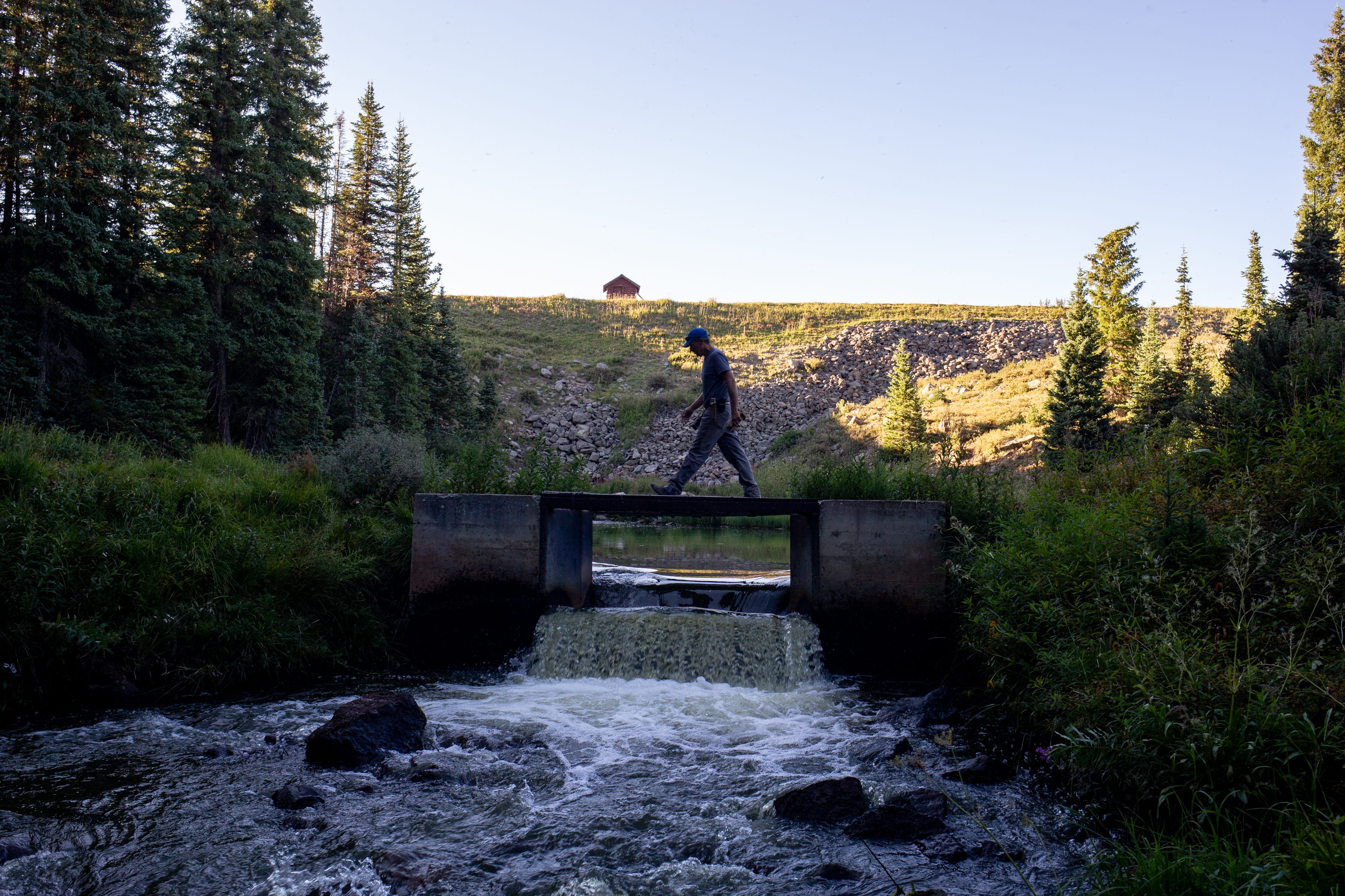 Water Commissioner John Walker walks across a 6-foot flume to get water flow measurements on Aug. 22, 2021, at Park Reservoir in the Grand Mesa National Forest in Colorado.