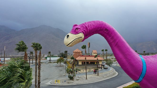 Rain begins to fall on the Cabazon Dinosaurs tourist attraction in Cabazon, Calif., the evening of October 25, 2021.