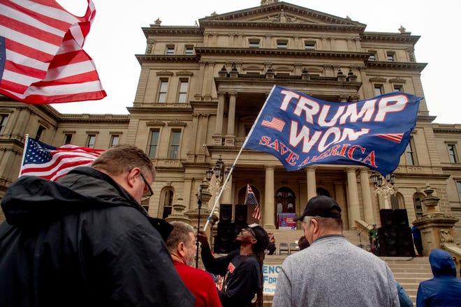 FILE - In this Oct. 12, 2021 file photo, a protester waves a Trump flag during rally at the Michigan State Capitol in Lansing, Mich.  Republicans have had wild success this year passing voting restrictions in states they control politically, from Georgia to Iowa to Texas.  (Jake May/The Flint Journal via AP, File)