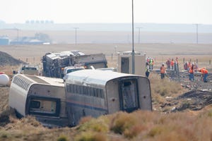 In this Sept. 27 file photo, workers stand near train tracks next to overturned cars from an Amtrak train that derailed near Joplin, Montana.
