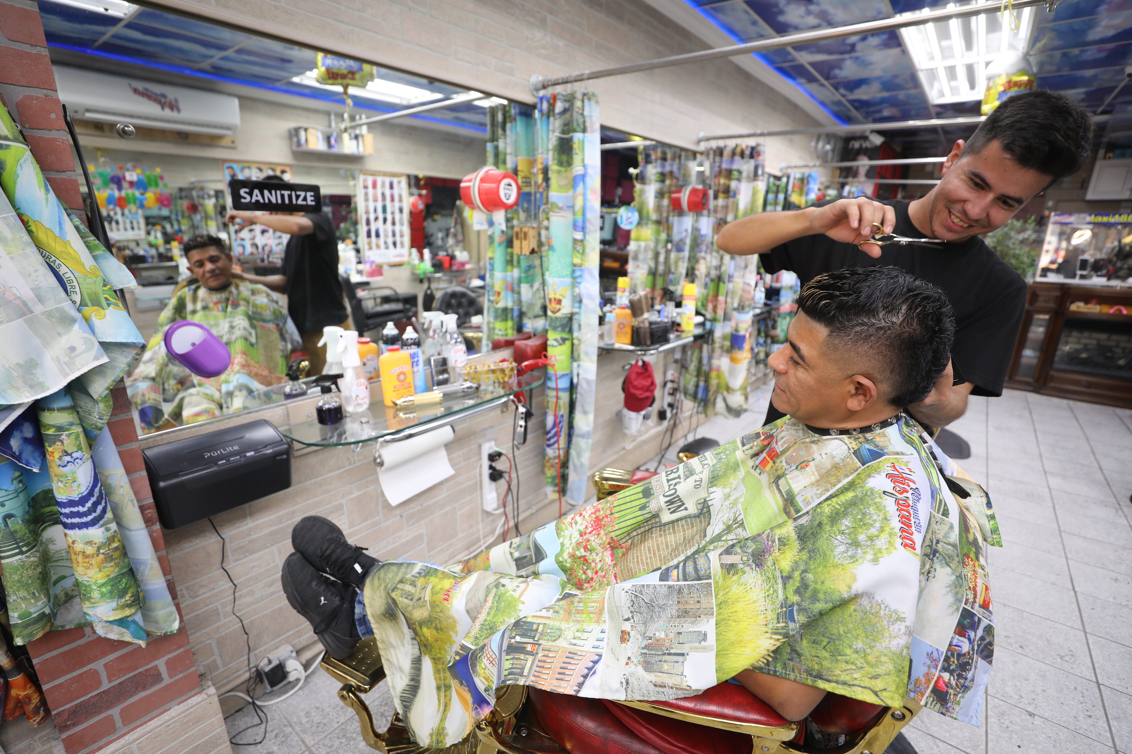 A person cycles past La Peluqueria Barber Shop on Speedwell Avenue on October 14, 2021. Inside the shop, owner Wilmer Valbuena has his hair cut by Cristian Castilla, of Morristown.