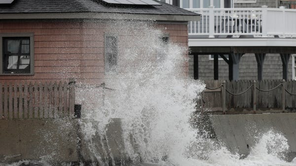 A wave crashes into the retaining wall of a home i